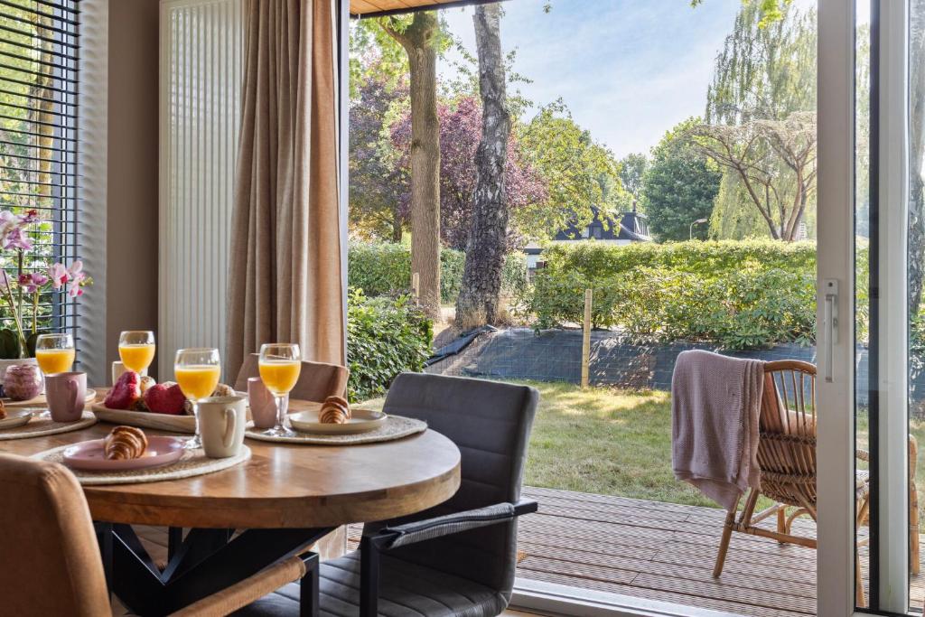 a dining room with a table and a large window at Lodge 't Hert - Nieuwe lodge met vrij uitzicht & omheinde tuin in Putten