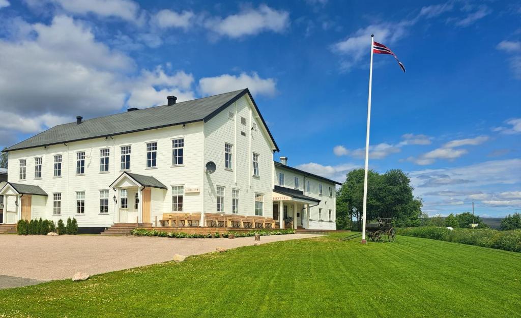 a large white building with a flag on a pole at Kjølen Hotel Trysil in Trysil