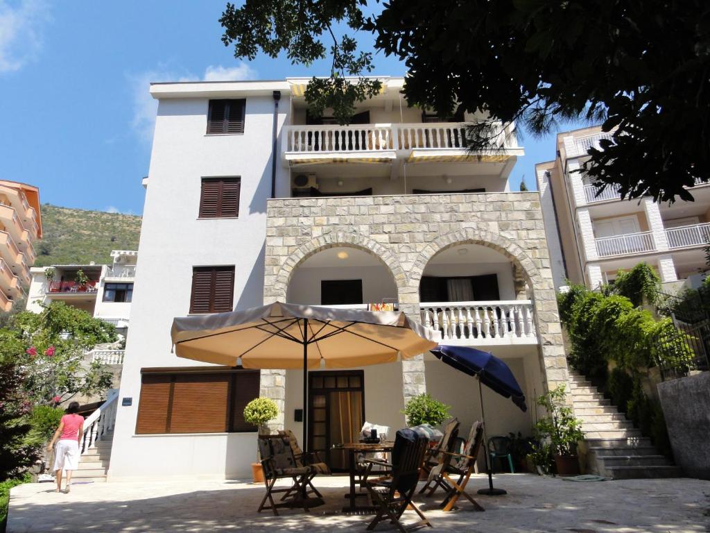 a building with a table and an umbrella in front of it at Apartmani Novakovic in Petrovac na Moru