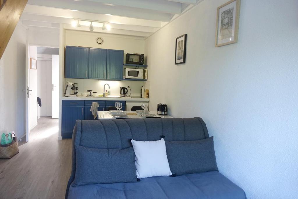 a living room with a blue couch and a kitchen at Arzon in Arzon