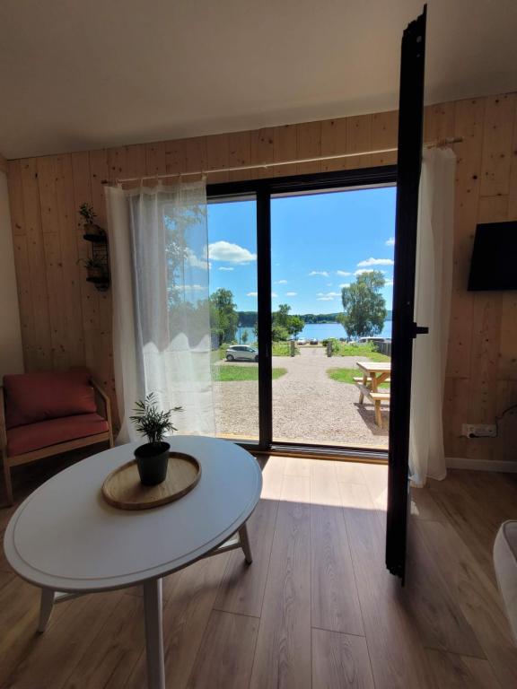 ein Wohnzimmer mit Tisch und großem Fenster in der Unterkunft Maison bord du Lac des Settons in Montsauche-les-Settons