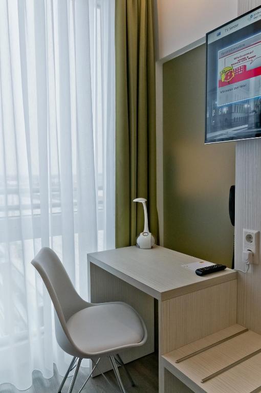 a room with a chair and a desk and a television at Super 8 by Wyndham Munich City North in Munich