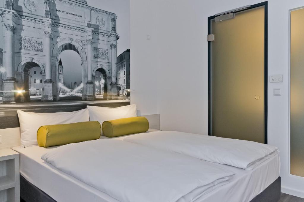 a bedroom with a white bed with a yellow pillow at Super 8 by Wyndham Munich City North in Munich