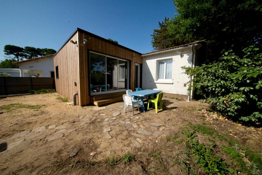 una casa con mesa y sillas en un patio en Maison avec jardin arboré et calme, en Jard-sur-Mer