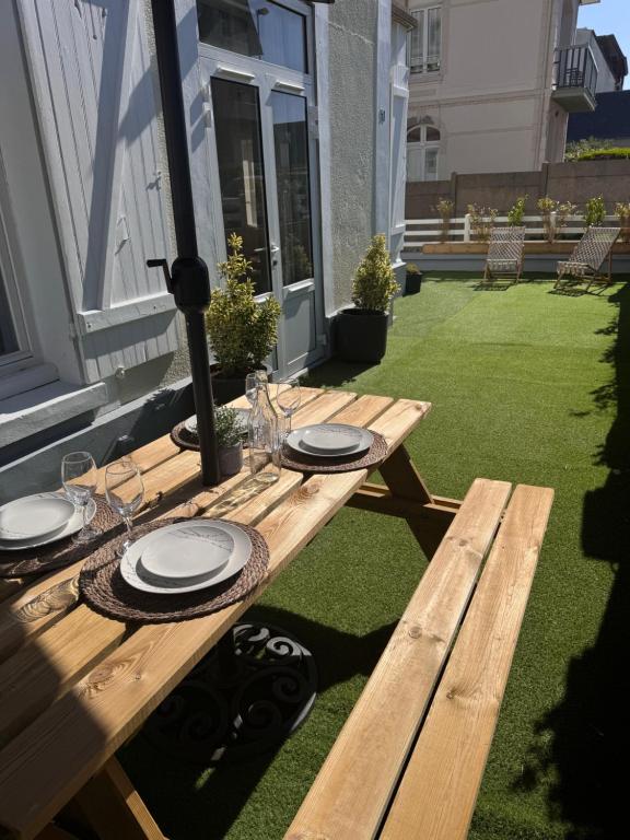 une table de pique-nique en bois avec des assiettes et des verres dessus dans l'établissement Les embruns, à Blonville-sur-Mer