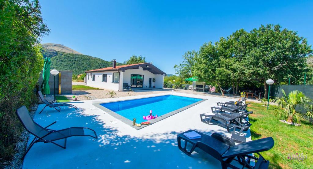 a swimming pool with chairs and a house at Holiday Home Nova Lux in Mostar