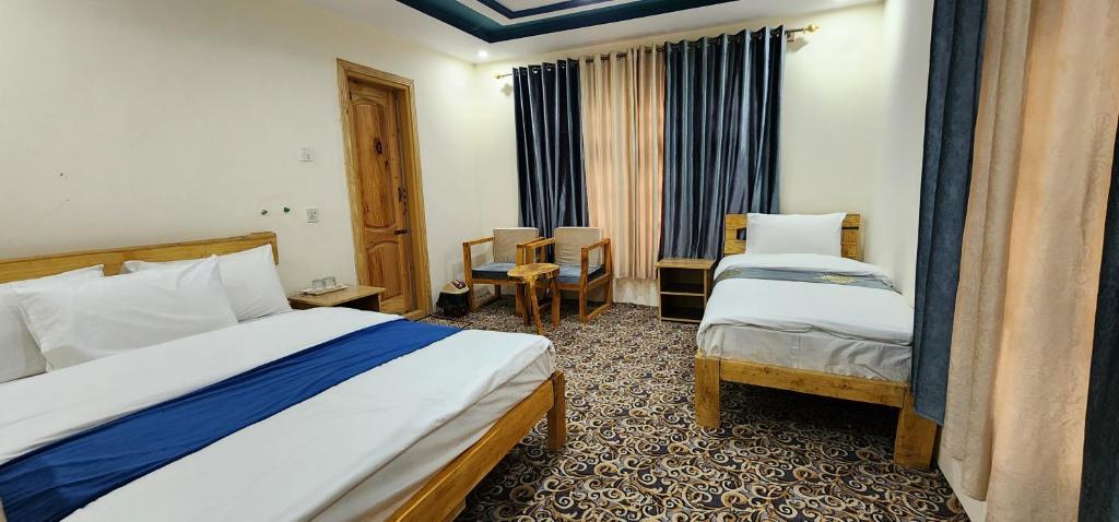 een hotelkamer met twee bedden en een tafel en stoelen bij Adventure Sarai Skardu in Skardu