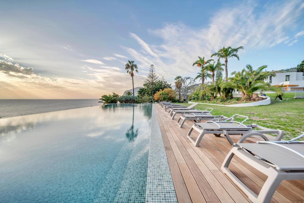 a pool with lounge chairs next to the ocean at In-Town Residences in Funchal