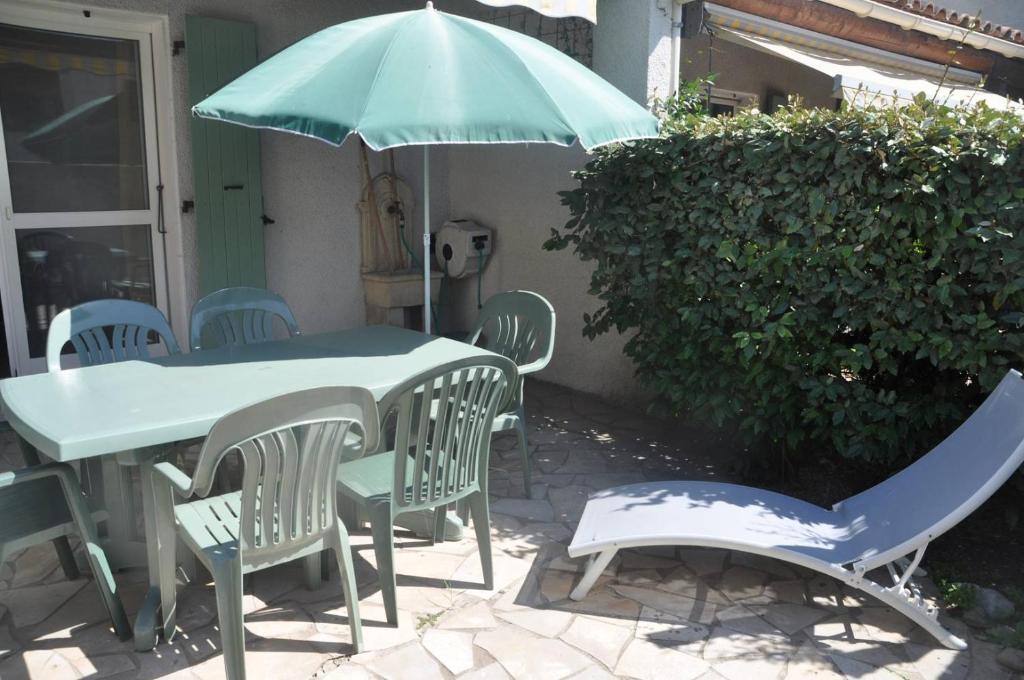 a green table and chairs with an umbrella at Appartement - 4 chambres - piscine collective- place de parking privée (garage) in Saintes-Maries-de-la-Mer