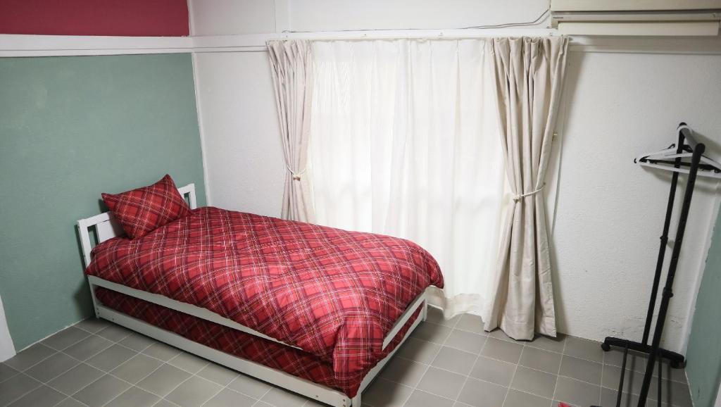 a bedroom with a bed with a red blanket and a window at Artist's Studio in Mitaka