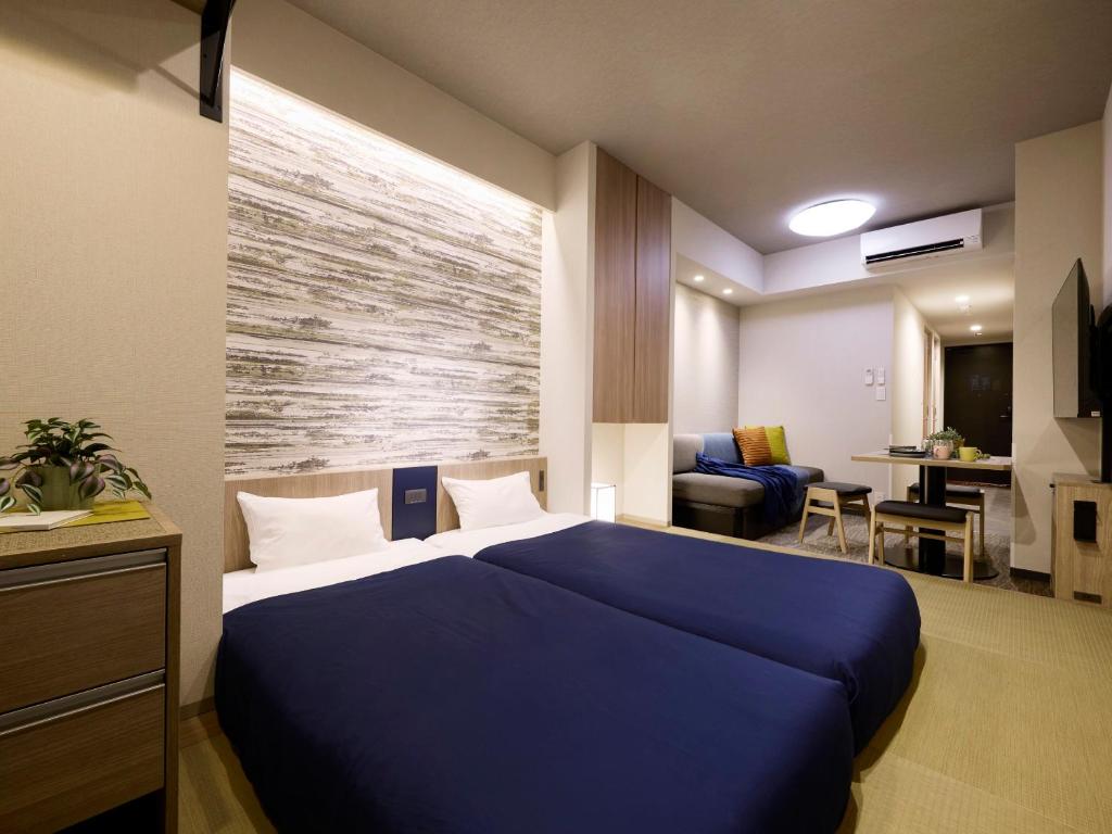 a bedroom with a blue bed and a living room at Minn Ueno Shin-Okachimachi in Tokyo