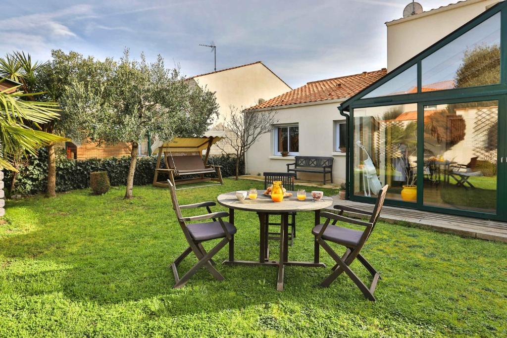 un patio avec une table et des chaises dans une cour dans l'établissement Maison authentique avec jardin, à Les Sables-dʼOlonne