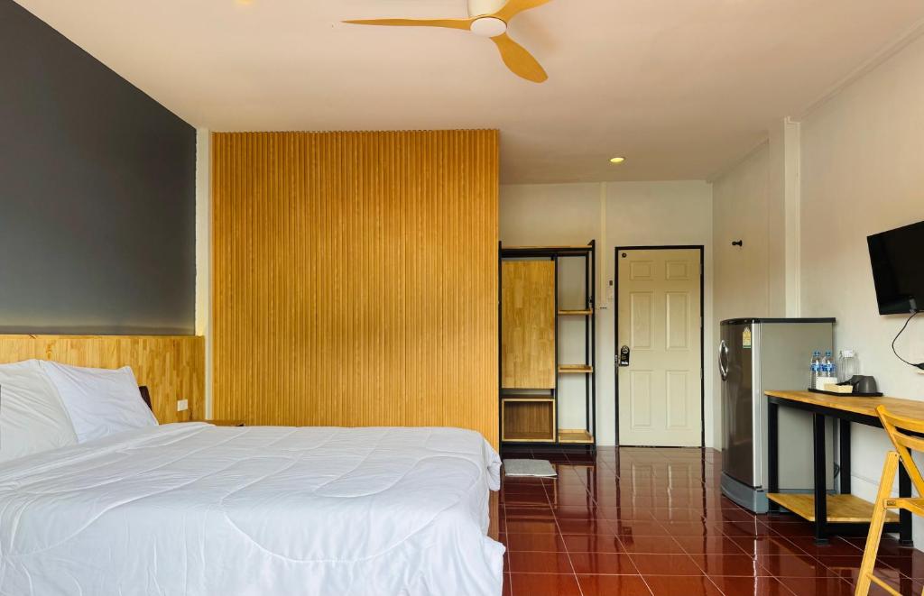 een slaapkamer met een bed, een bureau en een plafondventilator bij Henry’s House in Ban Ket Ho