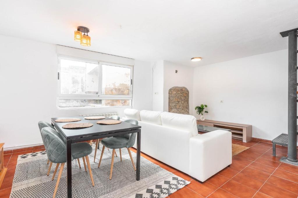 a living room with a white couch and a table at Maravillosa casa con jardín cerca de playa en centro de Asturias in Llodares