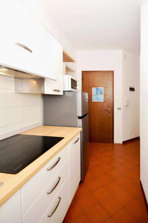 a kitchen with white cabinets and a refrigerator at Residence Garuda in Cavallino-Treporti