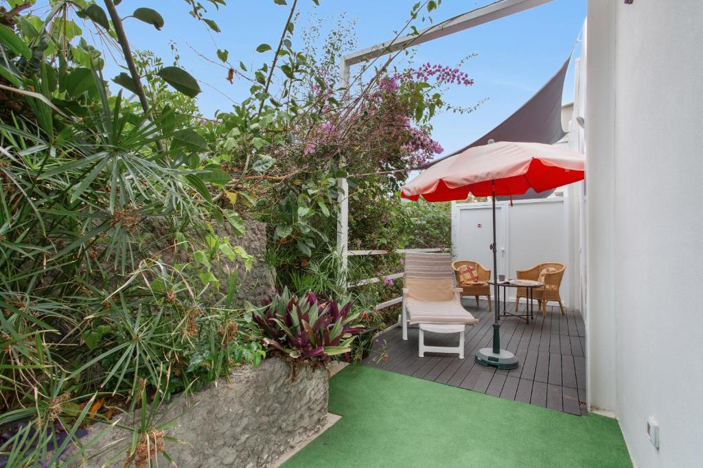 a patio with a table and an umbrella and some plants at Terrassenzeit 3 in Puerto de la Cruz