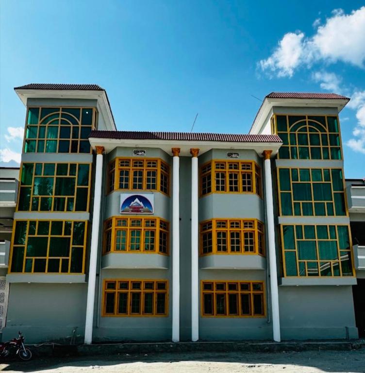a building with yellow windows and a blue sky at Adventure Sarai Skardu in Skardu