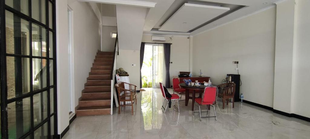 RADJIMIN Homestay في Adi Sutjipto: غرفة طعام مع طاولة وكراسي حمراء