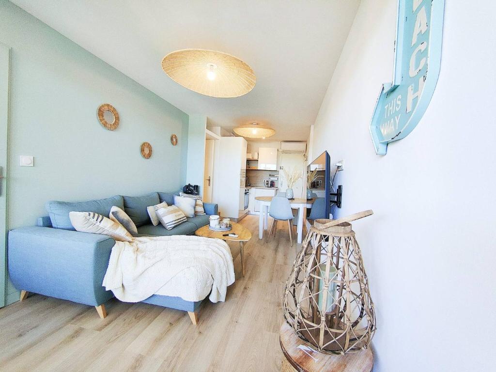 a living room with a blue couch and a kitchen at Le Cosy Les Pieds Dans L'eau in Le Grau-du-Roi