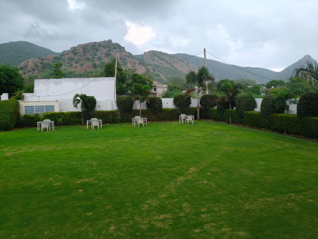 a lawn with tables and chairs in a yard with mountains at Sariska Celebration Hotel & Resort in Alwar