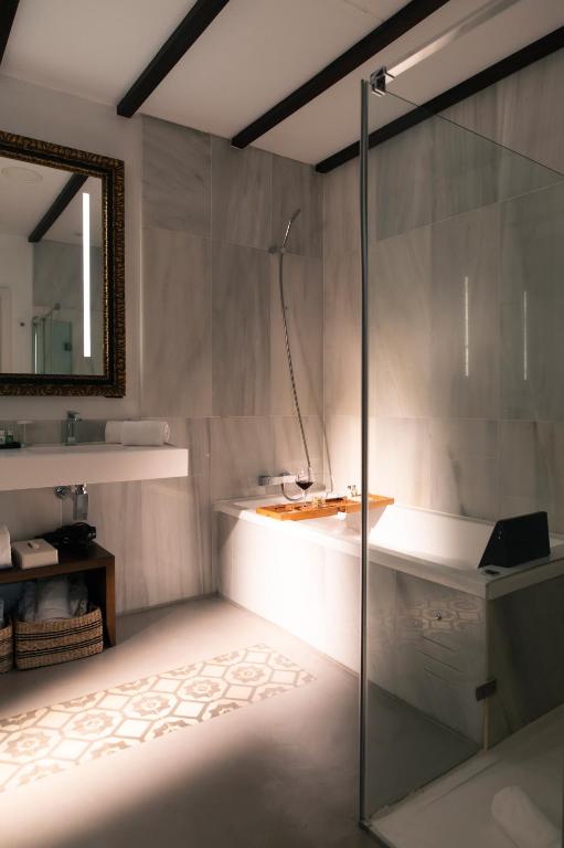 a bathroom with a shower and a sink and a tub at Hotel Legado Alcazar in Seville