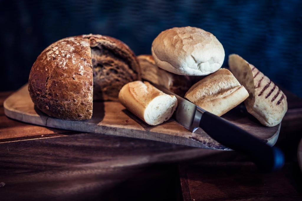 a cutting board with different types of bread and a knife at Carlton George Hotel in Glasgow