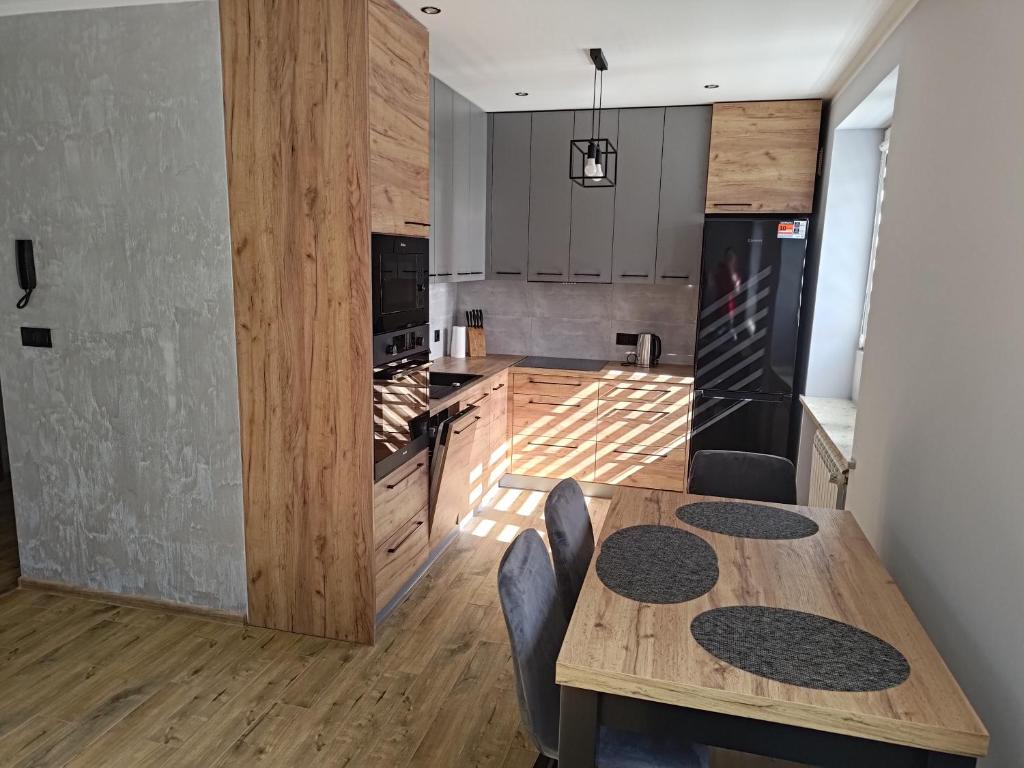 a kitchen with a wooden table and a dining room at Apartament u Jacka - 400m od Zamojskiej Starówki in Zamość