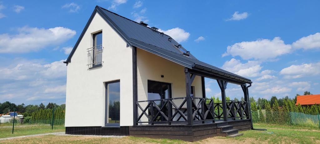 een klein wit huis met een zwart dak bij Domek nad jeziorem Potoczek, Giże in Giże