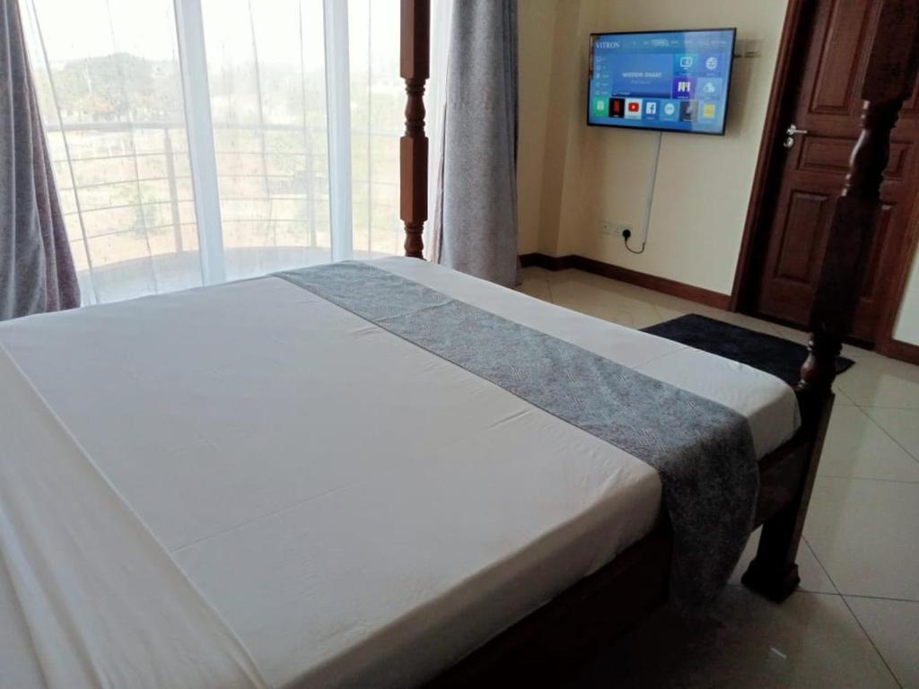 a bed in a room with a tv and a window at Iko homes in Mombasa
