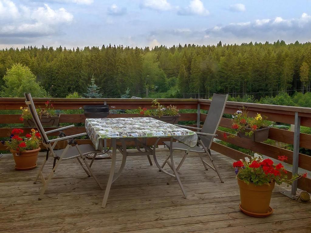 a table and two chairs on a deck with flowers at Ferienwohnung In Bad Elster Mit Grill, Terrasse Und Garten in Bad Elster