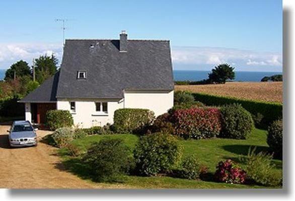 une maison avec une voiture garée devant dans l'établissement Komforthaus Mit Traumgarten Und Meerblick, à Plouha