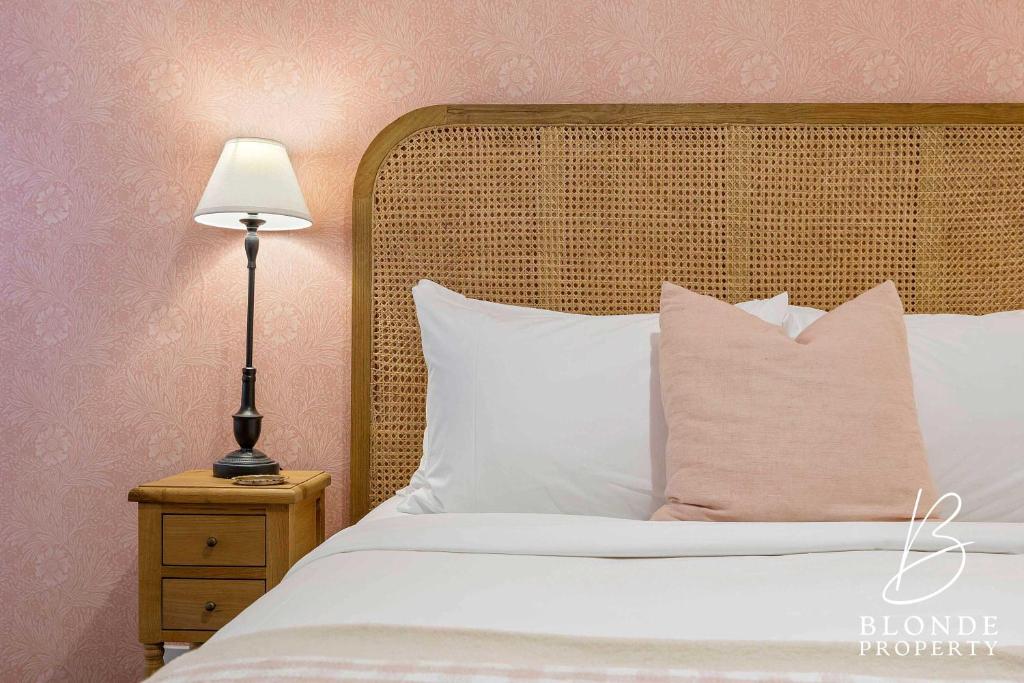 a bed with white pillows and a lamp on a night stand at Journeyman's Cottage in Ballarat