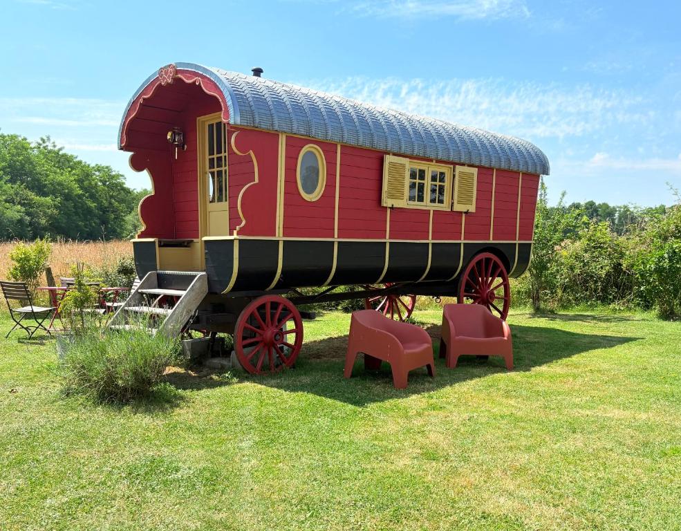 un vagón de tren rojo expuesto en un campo en La roulotte Champêtre des Grillots, en Beaulon