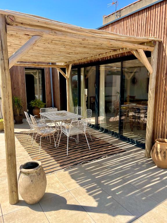 une pergola en bois avec une table et des chaises sur une terrasse dans l'établissement Nid douillet sur roof top, à Perpignan