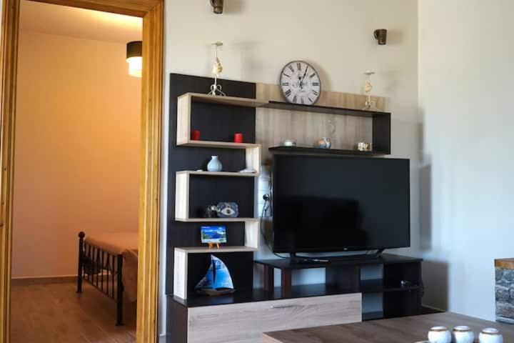 a living room with a tv and a clock on a wall at Dimitras house palaiopoli in Kythira