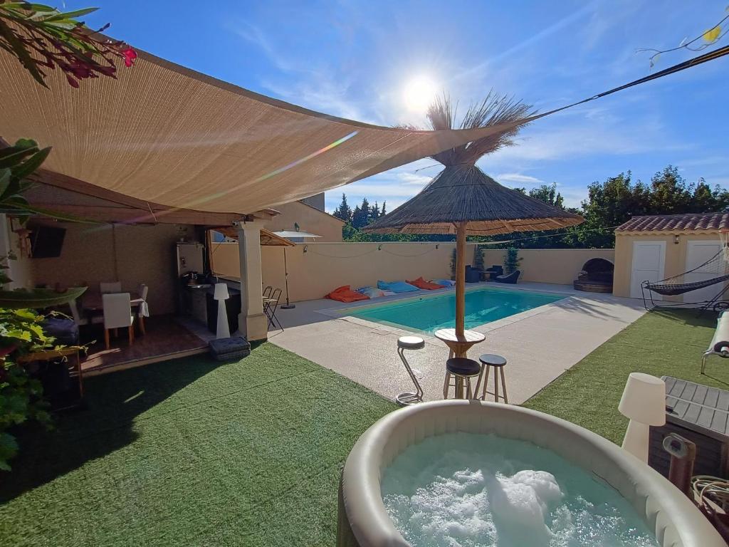a bath tub sitting in the grass next to a pool at Maison villa avec piscine et spa, 8 à 10 personnes in LʼIsle-sur-la-Sorgue