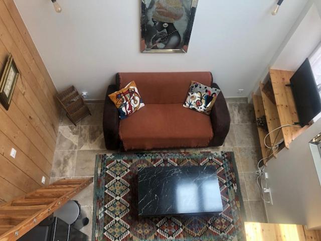 a brown couch in a living room with a table at La Chapelle de Monet - Logis Les Marguerites in Bois-Jérôme-Saint-Ouen