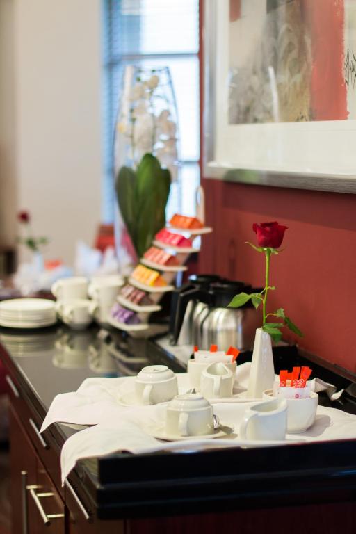 a kitchen counter with white dishes and a rose in a vase at City Lodge Hotel Sandton, Morningside in Johannesburg