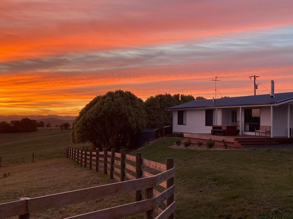 a house with a fence in front of a sunset at Oak Vue cottage in Korumburra