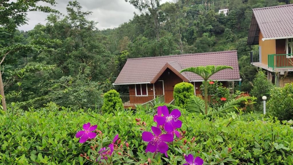una casa con fiori viola in primo piano di Don's River Valley Jungle Resort a Maraiyūr