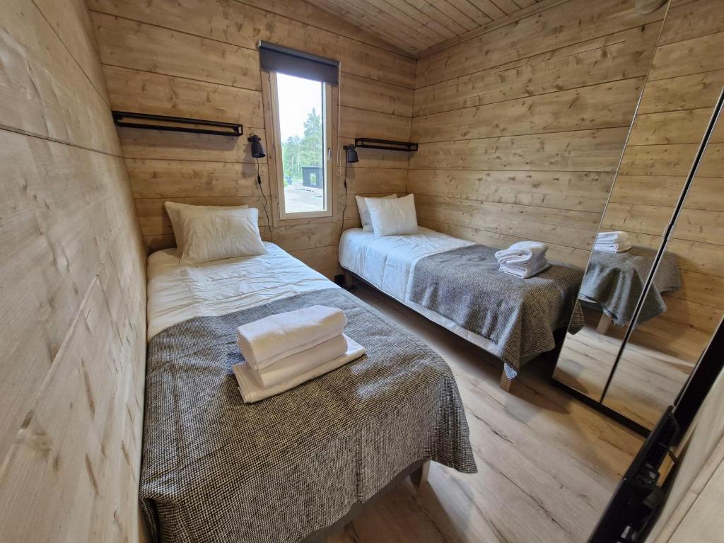 two beds in a room with wooden walls at Rauhalahti Holiday Homes in Kuopio
