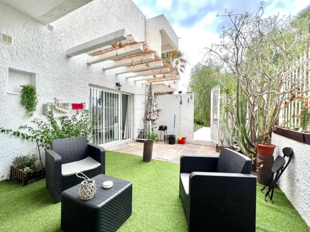 a patio with green grass and chairs and a building at Precioso Estudio con Terraza Privada y BBQ en Costa del Silencio in Costa Del Silencio