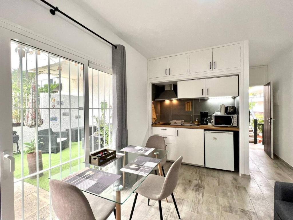 Una cocina y un comedor con una mesa de cristal y sillas. en Precioso Estudio con Terraza Privada y BBQ en Costa del Silencio, en Costa del Silencio