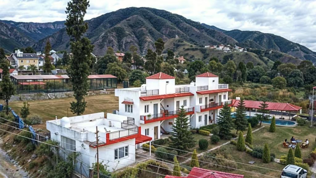 a large white building with mountains in the background at Mohdev Resort in Jhājra