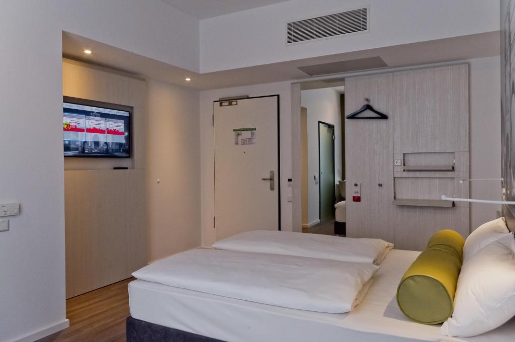 a bedroom with a bed and a tv on a wall at Super 8 by Wyndham Munich City North in Munich