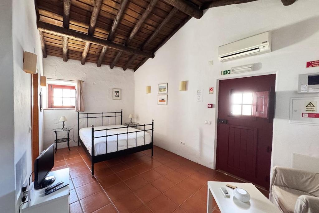 a bedroom with a bed and a tv in a room at Casinha do Chafariz - Casas da Amieira in Amieira