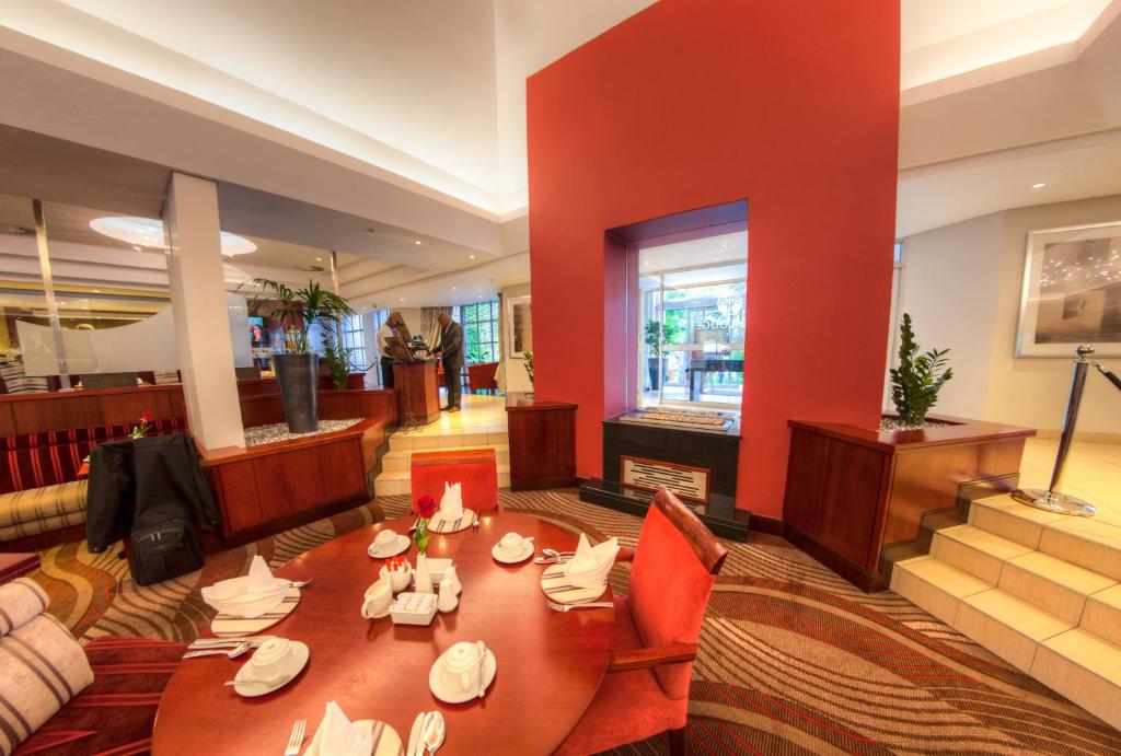 a dining room with a table and a red wall at City Lodge Hotel Sandton, Morningside in Johannesburg