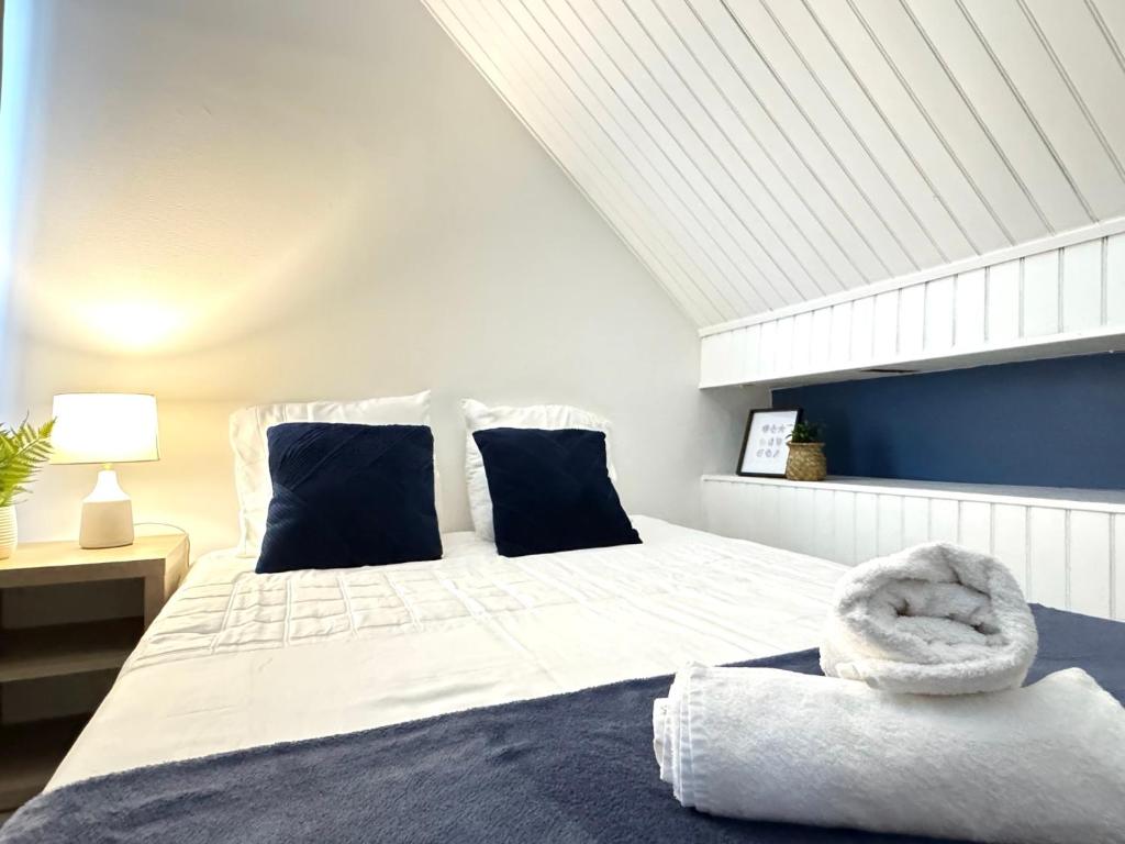 a bedroom with a large white bed with blue pillows at Appartement Platanes 6 - Proche Disney - Parking Gratuit - Meaux in Meaux