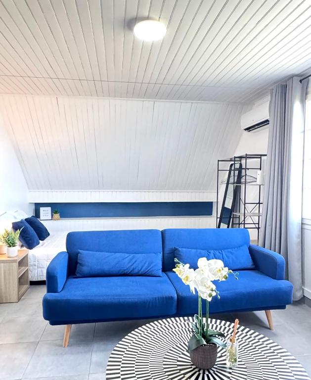 - un salon avec un canapé bleu et un lit dans l'établissement Appartement Platanes 6 - Proche Disney - Parking Gratuit - Meaux, à Meaux