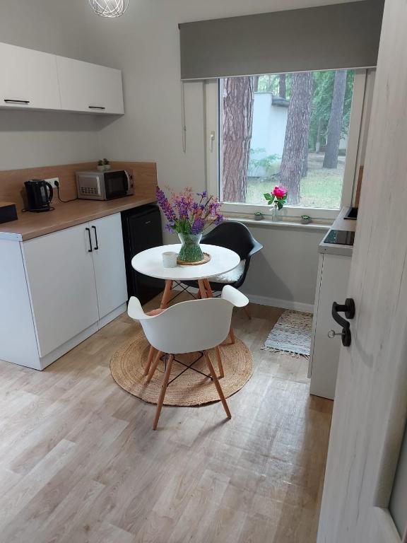 a kitchen with a table with a vase of flowers on it at W sosnowym lesie in Lubniewice